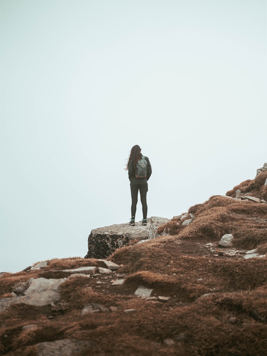 man in black jacket standing on brown rock during daytime